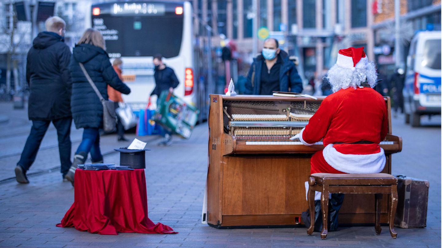 Schwerin: Weihnachtslieder in der Fußgängerzone  Kurz vor dem zweiten Lockdown: Ein als Weihnachtsmann verkleideter Straßenmusikant spielt in der Innenstadt auf seinem mobilen Klavier.