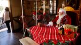 Los Angeles: Mit Plexiglas geschützt  Ein als Weihnachtsmann verkleideter Mann sitzt aufgrund der Ansteckungsgefahr mit dem Coronavirus hinter Plexiglaswänden in einem Raum in den "Citadel Outlets".
