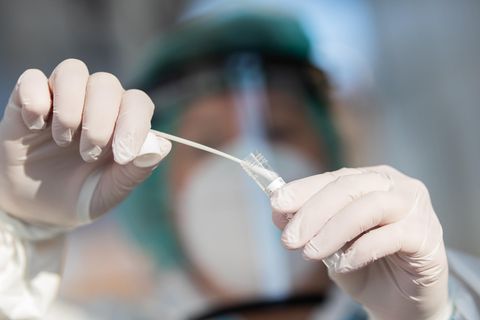 Eine Mitarbeiterin eines Gesundheitsamtes füllt einen Corona-Abstrich in ein Röhrchen