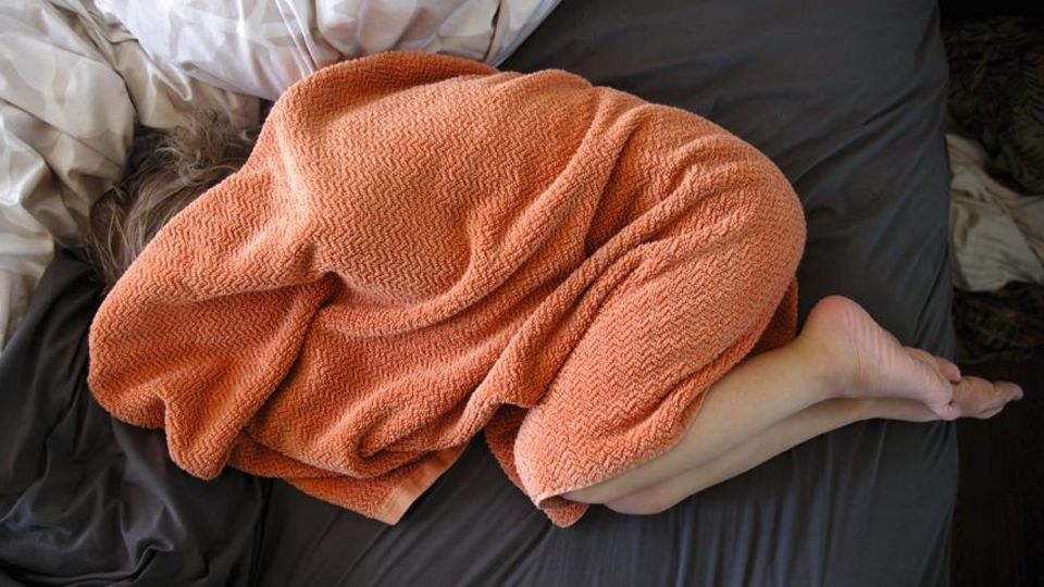 Eine Frau kauert unter einer Decke Eine Frau kauert unter einer Decke