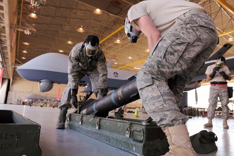 Zwei US-Soldaten munitionieren eine Drohne mit Hellfireraketen.