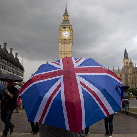 Eine Person mit einem Union-Jack-Regenschirm steht vor Big Ben in London