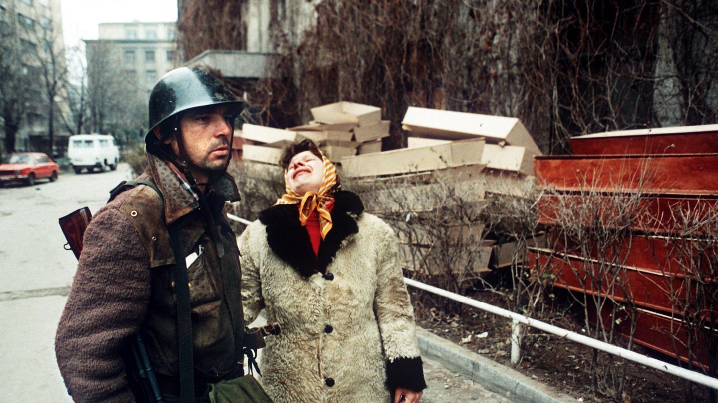 Das Jahr 1989 war das Jahr, in dem der Eiserne Vorhang fiel und es in vielen kommunistischen und sozialistischen Staaten des Ostblocks – etwa in Ungarn, Polen und der DDR – zu friedlichen Regimewechseln und später zu freien Wahlen kam. In Rumänien verlief die Revolution blutig, wie dieses Foto zeigt. Ein Soldat steht neben einer Frau, die soeben vom Tod ihres Sohnes erfahren hatte, aufgenommen am 25.12.1989. Nach dem Sturz des Diktators Nicolae Ceausescu am 22. Dezember 1989 herrschten in Rumänien bürgerkriegsähnliche Zustände. Mitglieder der Geheimpolizei Securitate, Schergen des selbsternannten "Conducator" (Führer) Ceausescu, lieferten sich mit der auf der Seite des Volkes kämpfenden Armee erbitterte Kämpfe. Ceausescu und seine Frau wurden auf der Flucht verhaftet und am 25. Dezember 1989 von einem militärischen Sondergericht zum Tode verurteilt und erschossen. Nach der Hinrichtung herrschte große Befriedung in Rumänien, aber kein Jubel. 