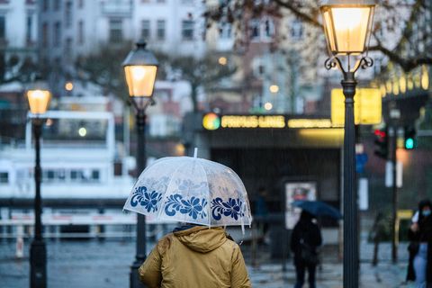 Eine Frau geht mit ihrem Schirm über den Römerberg in Frankfurt