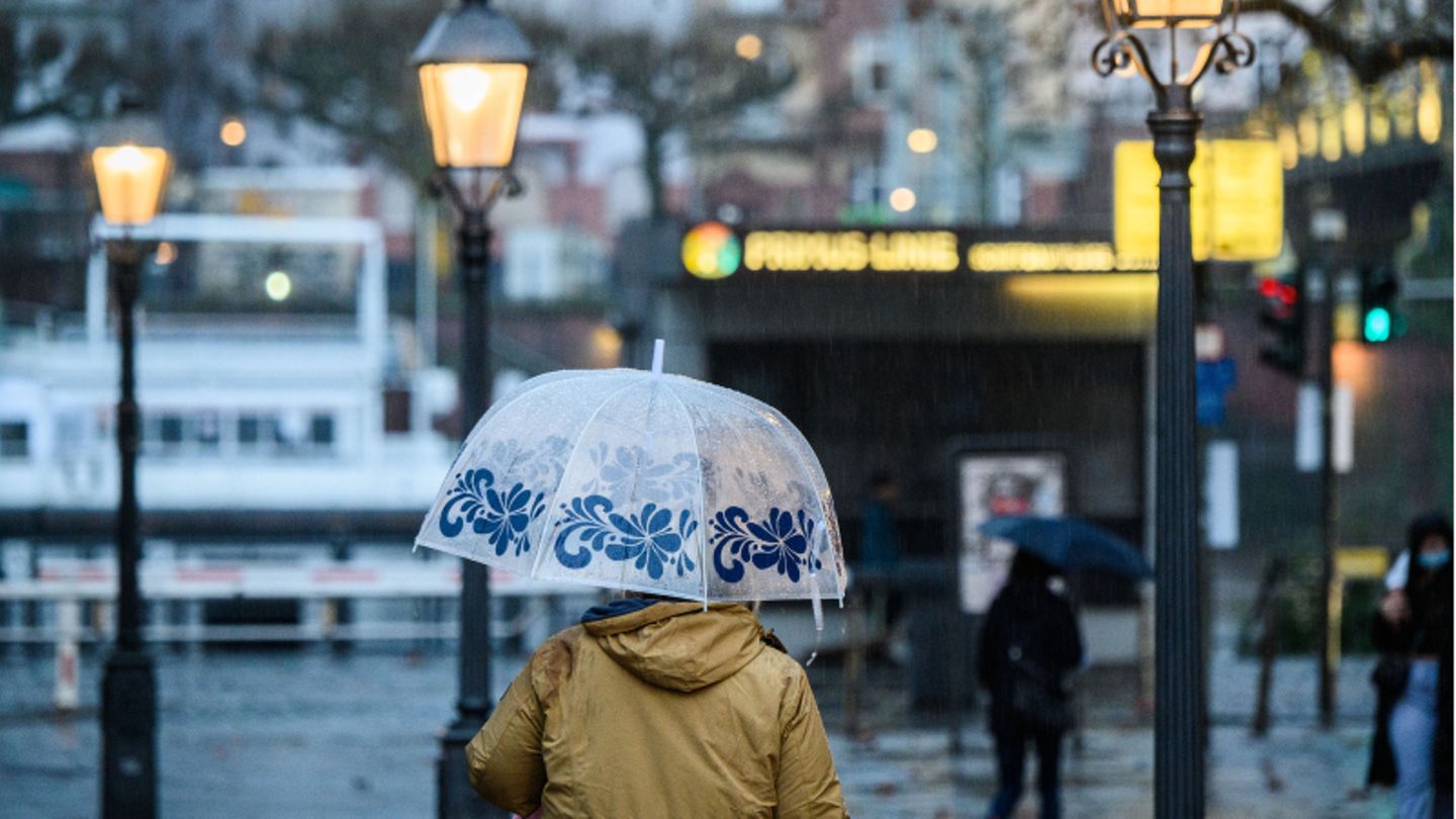 Eine Frau geht mit ihrem Schirm über den Römerberg in Frankfurt