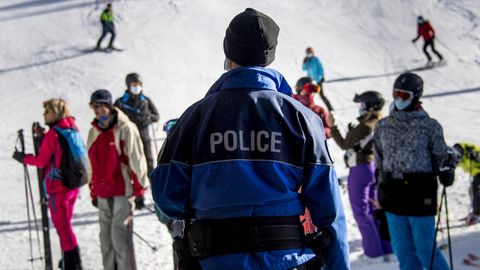 Ein Polizist kontrolliert Ski-Fahrer auf einer Piste im Walliser Skigebiet auf das Tragen von Mund-Nasen-Bedeckungen.
