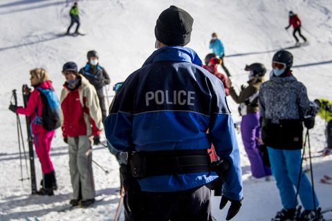 Ein Polizist kontrolliert Ski-Fahrer auf einer Piste im Walliser Skigebiet auf das Tragen von Mund-Nasen-Bedeckungen.