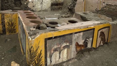 Pompeji, Italien: Die fast intakten Räumlichkeiten eines Thermopoliums, eines Straßenrestaurants. Seine gut erhaltenen, farbenfrohen Fresken zeigen Gänse, einen Hahn, einen Hund an der Leine und mythologische Charaktere.