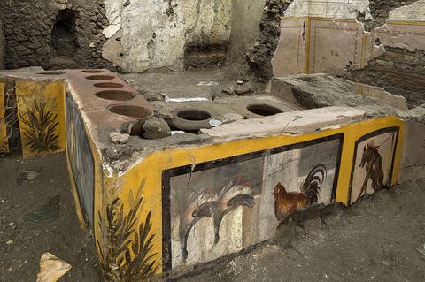 Pompeji, Italien: Die fast intakten Räumlichkeiten eines Thermopoliums, eines Straßenrestaurants. Seine gut erhaltenen, farbenfrohen Fresken zeigen Gänse, einen Hahn, einen Hund an der Leine und mythologische Charaktere.