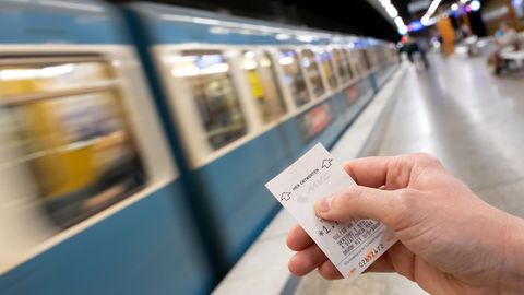 Eine Frau hält an einer U-Bahn-Station in München ein MVG-Ticket in der Hand