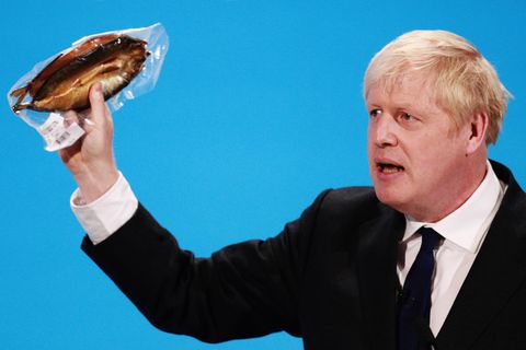 Boris Johnson hält einen eingeschweißten Räucherfisch hoch