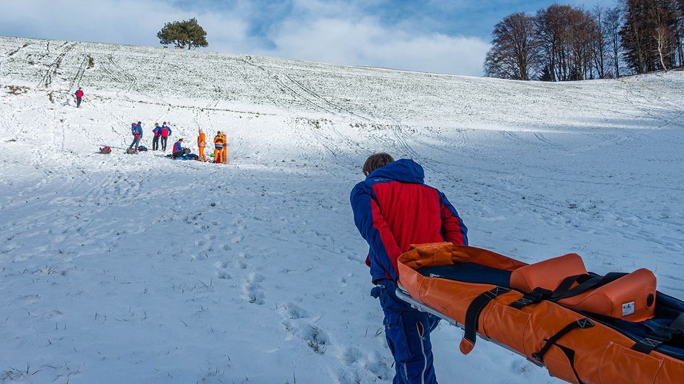 Ein Retter der Bergwacht kommt mit einer Trage