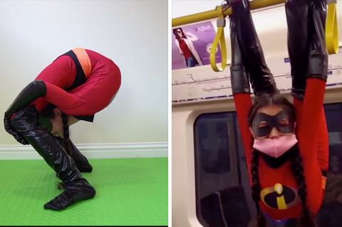 Ein Mädchen in einem rot-schwarzen Superhelden-Anzug beugt sich so weit nach hinten, dass ihr Kopf zwischen den Knien ist