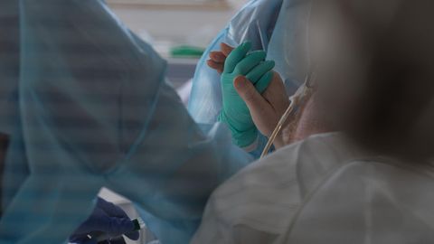 Eine Ärztin hält in der Intensivstation des Luisenhospitals die Hand eines Coronapatienten.