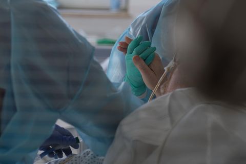Eine Ärztin hält in der Intensivstation des Luisenhospitals die Hand eines Coronapatienten.