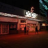 Vor dem geschlossenen Musikklub "Docks" an der Reeperbahn in Hamburg gehen drei junge Männer bei Nacht vorbei