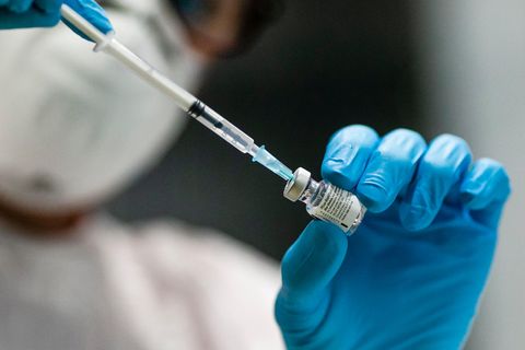 Eine Mitarbeiterin des Kieler Impfzentrums zieht mit einer Kanüle den Impfstoff aus einer Glasampulle auf.