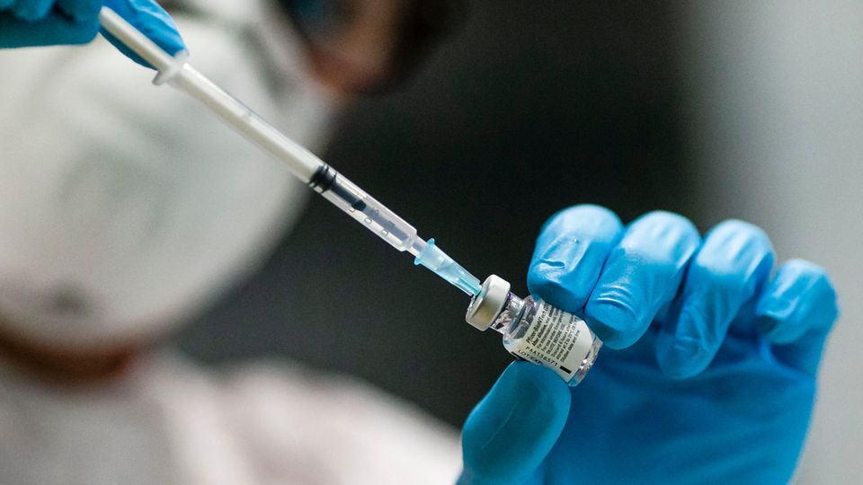 Eine Mitarbeiterin des Kieler Impfzentrums zieht mit einer Kanüle den Impfstoff aus einer Glasampulle auf.