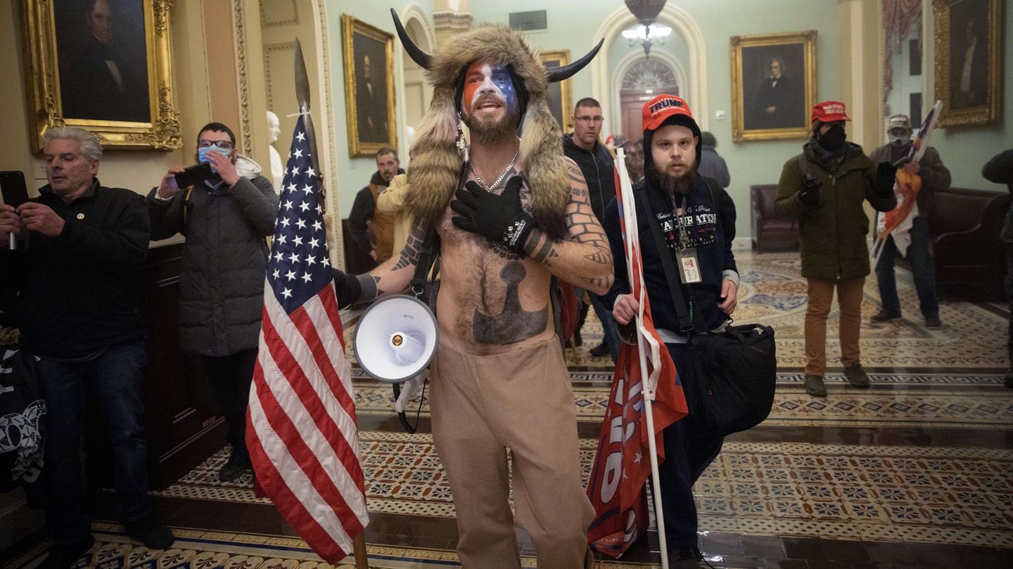 Eindringlinge rücken vor der Senatskammer auf die Sicherheitskräfte zu. Der halbnackte Mann mit den Hörnern ist Jacob Chansley. Er wird als der "Qanon-Schamane" bekannt, wegen seines Outfits und weil er sich in Interviews zu der rechtsextremen Verschwörungsbewegung bekennt