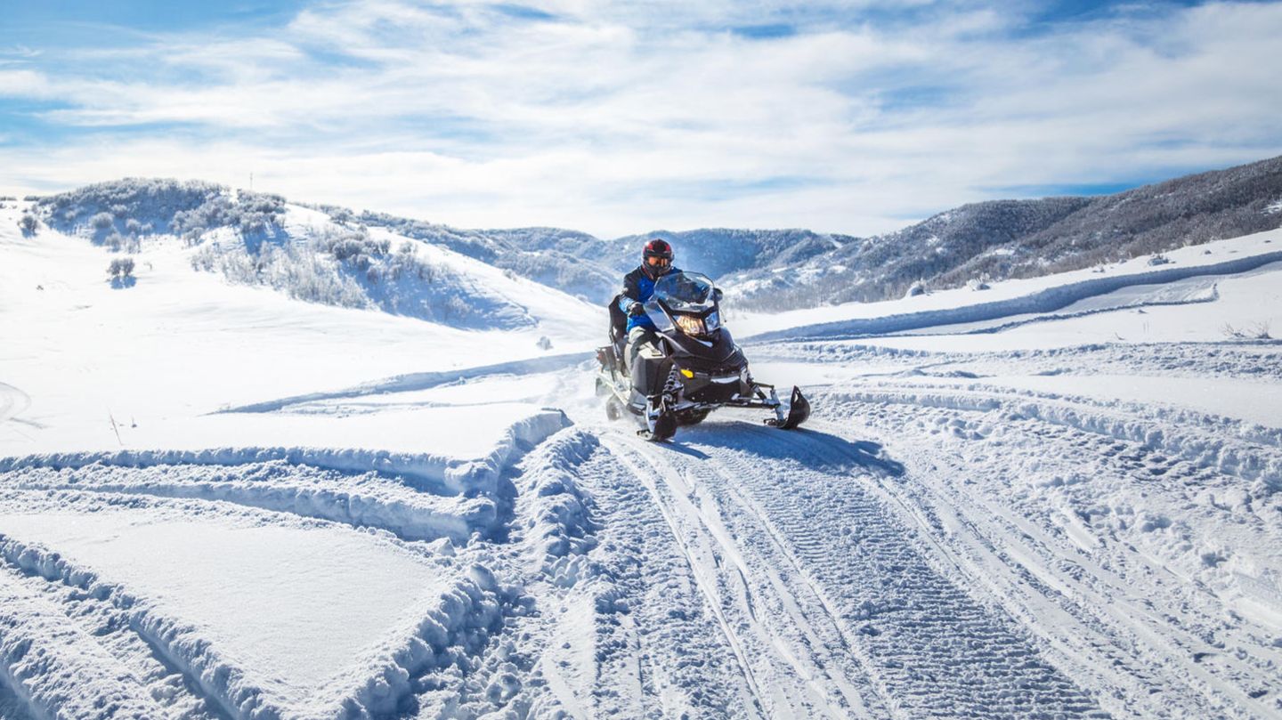 Eine Person auf einem Motorschlitten in verschneiter Landschaft