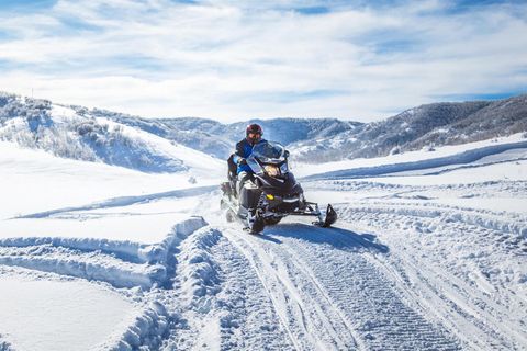 Eine Person auf einem Motorschlitten in verschneiter Landschaft