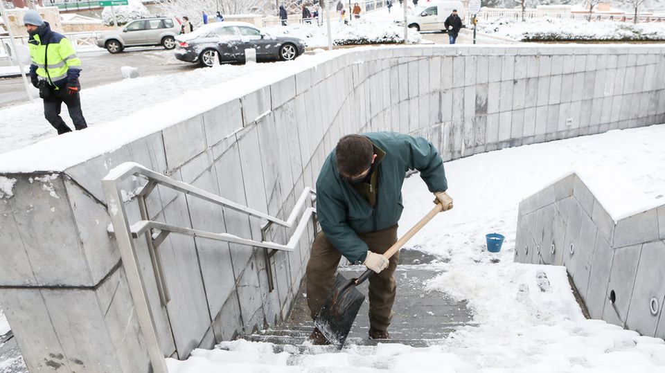 Schnee Spanien Kälte Mann Schaufel treppe Ein Mann in dunkelgrüner Jacke und brauner Hose schaufelt Schnee von den Stufen einer steinernen Treppe