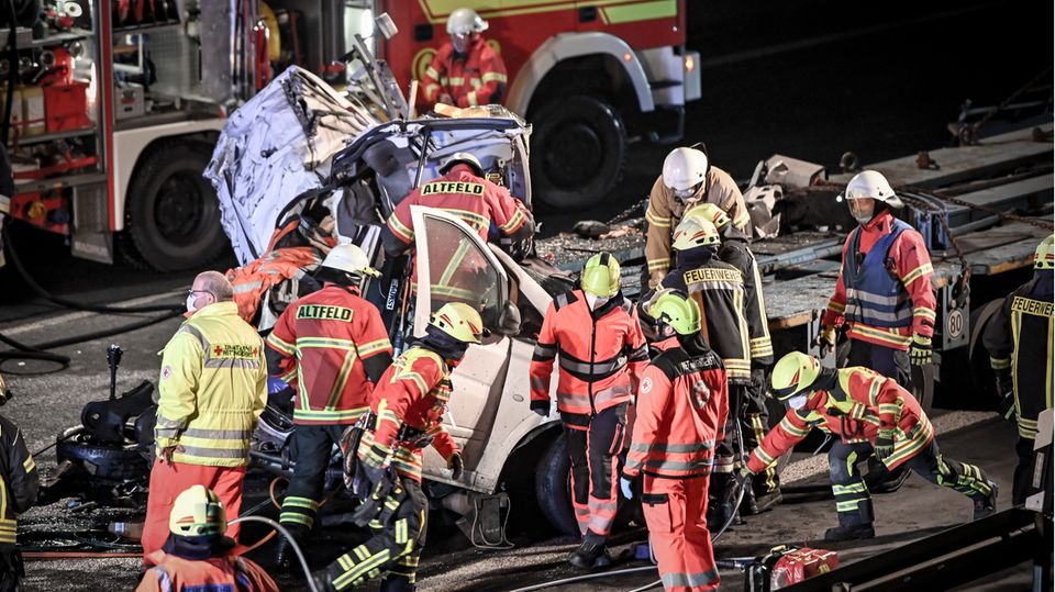 Rettungskräfte stehen um ein völlig zerstörtes Fahrzeug