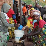Eine Wählerin hat ihren Personalausweis im Mund und wäscht sich die Hände, bevor sie zur Wahlurne geht.