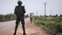Soldat steht bewaffnet auf einer leeren Straße.