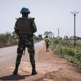 Soldat steht bewaffnet auf einer leeren Straße.