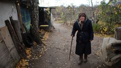 Eine alte Dame steht neben ihrem verlassenen Haus nahe Stanytsia Luhanska.