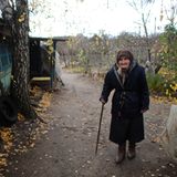 Eine alte Dame steht neben ihrem verlassenen Haus nahe Stanytsia Luhanska.
