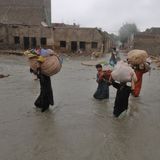 Anwohner tragen ihre Habseligkeiten während sie durch ein durch Monsunregen stark überschwemmtes Gebiet waten
