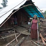 Eine verletzte Frau steht vor ihrer Holz-Hütte.
