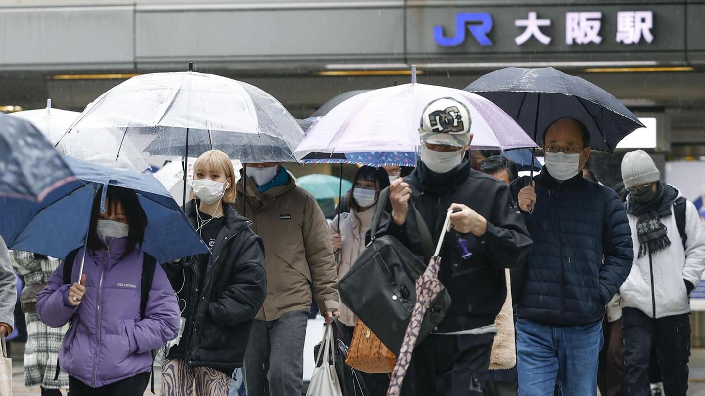 Menschen mit Mund-Nasen-Schutz gehen im Stadtteil Umeda in der Metropole Osaka über einen Fußgängerüberweg