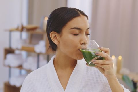 Frau tinkt Saft aus einem Glas.