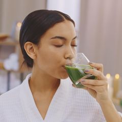 Frau tinkt Saft aus einem Glas.