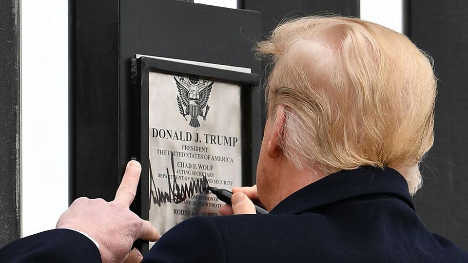 Donald Trump Mauer Mexiko Unterschrift US-Präsident Donald Trump ist von hinten zu sehen, während er auf einer Urkunde mit seinem Namen an einer Mauer unterschreibt