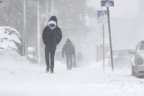 Zwei Passanten gehen in Helsinki über einen verschneiten Gehweg