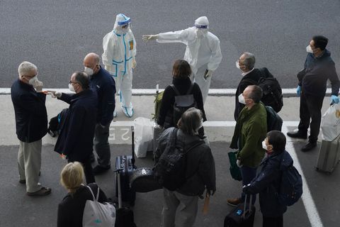 Arbeiter in Schutzkleidung sprechen mit WHO-Mitgliedern am Flughafen in Wuhan