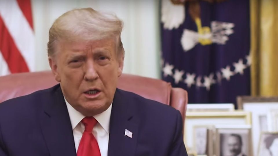 Donald Trump Video-Botschaft US-Präsident Donald Trump sitzt in einem Büro des Weißen Hauses an einem hölzernen Schreibtisch und spricht