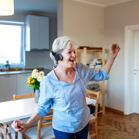 Frau mit Kopfhörern tanzt in Küche